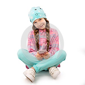 Happy little girl with smartphone sitting on floor isolated on white background. People, children, technology concept