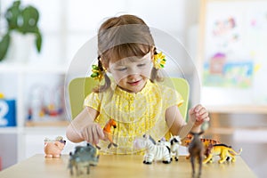 Happy little girl. Smiling child toddler plays animal toys at home or kindergarten.