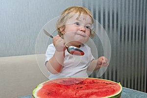 One-year-old girl eats watermelon with a spoon, the first independent use of vitamins, sweet berry