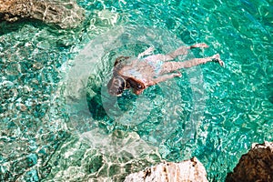 Happy little girl in snorkeling mask dive underwater with tropical fishes