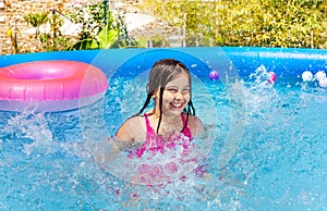 Happy little girl splash water in swimming pool