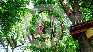 Happy little girl in summer. Hike and kids concept. Beautiful Little girl climbing and having fun in adventure Park