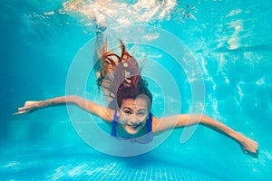 Happy little girl swim underwater in the pool