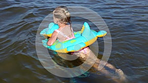 Happy little girl swimming on an inflatable crocodile toy in the sea