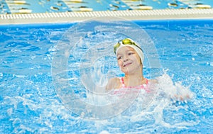 Happy little girl swimming in the pool. Caucasian child is playing fun in the kindergarten pool
