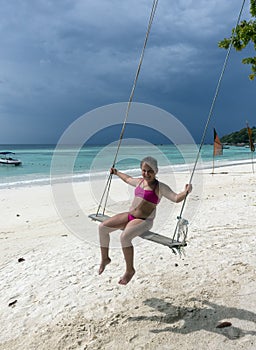 Happy little girl on swing at the beach