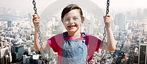 Happy little girl swinging on swing over city