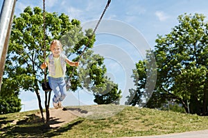 Happy little girl swinging on swing at playground