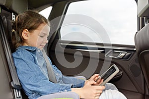 Happy little girl with tablet pc driving in car