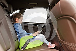 Happy little girl with tablet pc driving in car