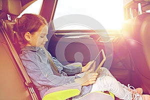 Happy little girl with tablet pc driving in car