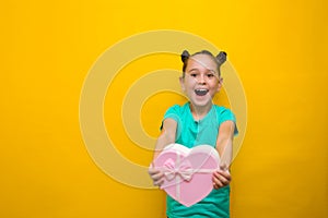 Happy little girl with tails standing isolated over yellow background holding shopping pink bag. smiles thoughtfully