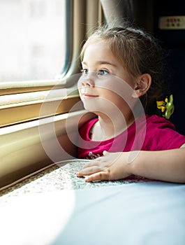 Happy little girl traveling by train.