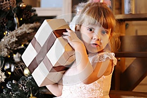 Happy little girl try to open christmas gift box