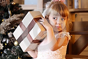 Happy little girl try to open christmas gift box