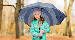 Happy little girl with umbrella at autumn park