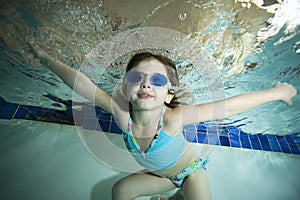 Happy little girl underwater in pool