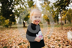 Happy little girl walking in the park in autumn. Beautiful female kid on yellow background