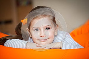 Happy little girl wallows in an orange bean bag chair