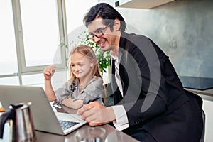 Happy little girl watching a movie on the computer with her father