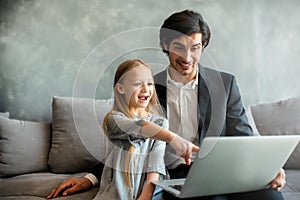 Happy little girl watching a movie on the computer with her father