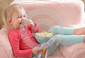 Happy little girl watching TV at home