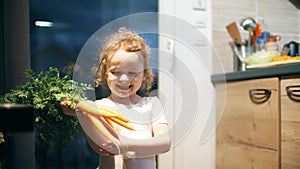 Happy little girl wearing ballerina costume dances with fresh carrots in the kitchen. Healthy eating concept