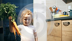 Happy little girl wearing ballerina costume dances with fresh carrots in the kitchen. Healthy eating concept