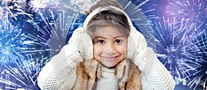 Happy little girl wearing earmuffs over firework