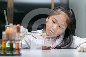 Happy little girl wearing lab coat making experiment photo