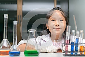 Happy little girl wearing lab coat making experiment photo
