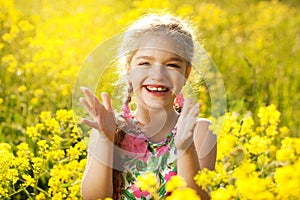 Happy little girl among yellow wildflowers