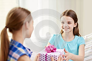 Happy little girls with birthday present at home