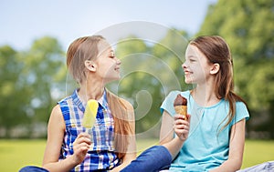 Happy little girls eating ice-cream in summer park