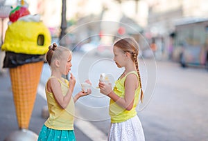 Happy little girls eating ice-creamin open-air cafe. People, children, friends and friendship concept