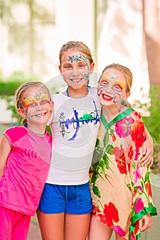 Happy little girls with face art paint in the park.