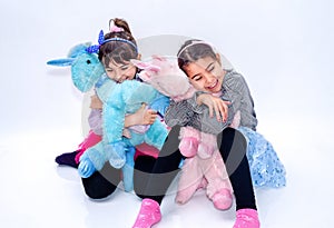 Happy little girls holding unicorn toys isolated on white