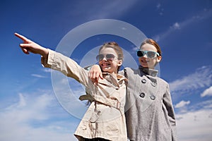 Happy little girls hugging and pointing finger