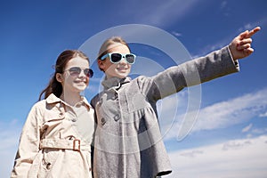 Happy little girls hugging and pointing finger