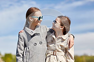 Happy little girls hugging and talking outdoors