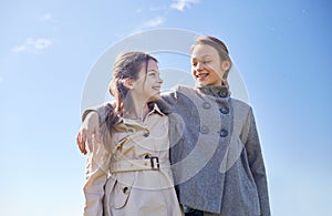 Happy little girls hugging and talking outdoors