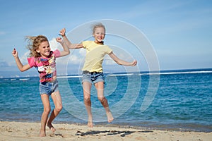 Happy little girls jumping on beach