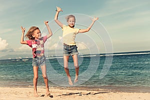 Happy little girls jumping on beach