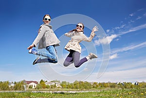 Happy little girls jumping high outdoors