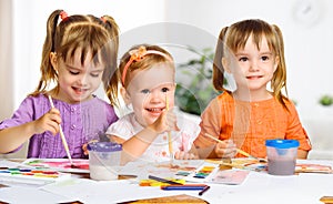 Happy little girls in kindergarten draw paints