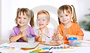 Happy little girls in kindergarten draw paints