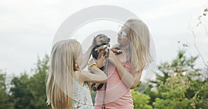 Happy little girls playing with dog in the park and having fun sisters together