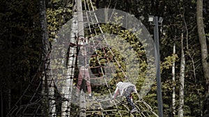 Happy little girls playing on the playground. Action. Kids having fun with the climbing net outdoors near green early