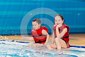 Happy little girls in a red vest swimming in the pool of the water park. Child learns to swim. teaching a child to swim