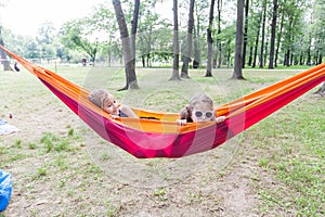 Happy little girls relax on hammock in nature